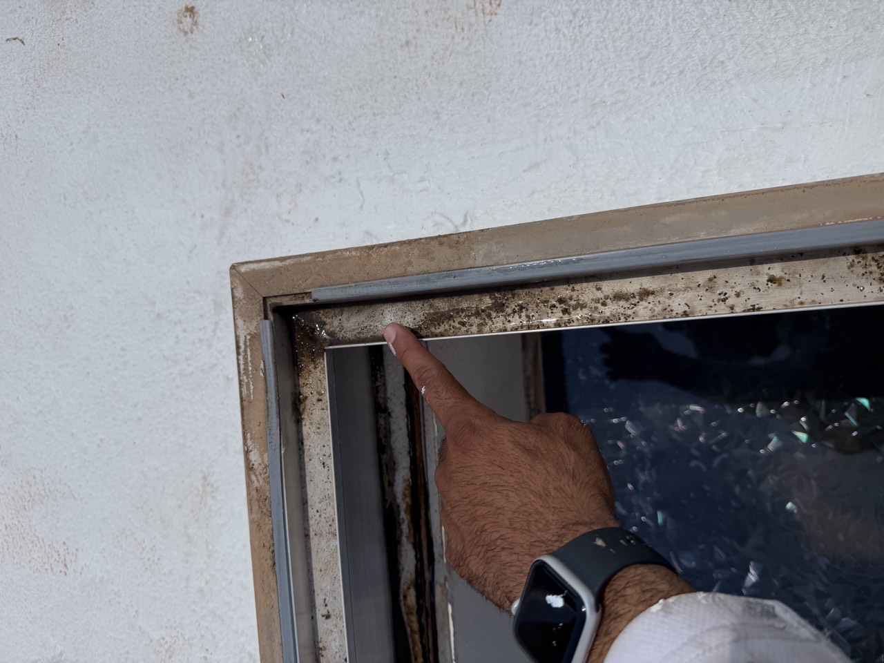 Interior view of a skylight well showing accumulated debris and dark staining along the metal frame