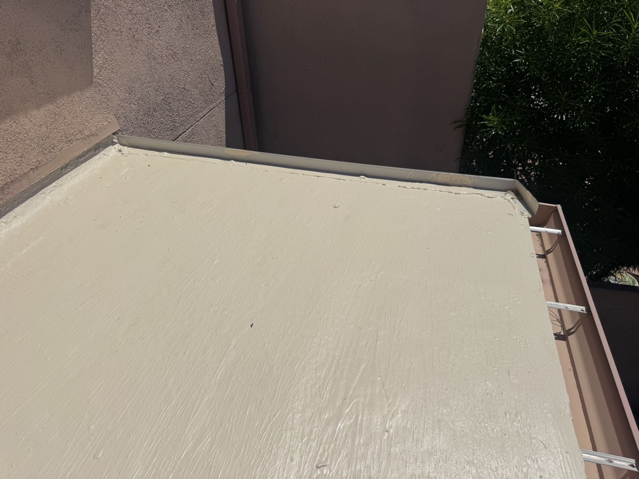 Completed tan roof coating along a parapet wall