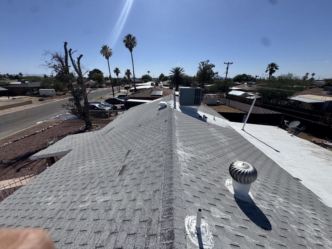 Shingle roof ridge line with new coating on adjacent flat roof